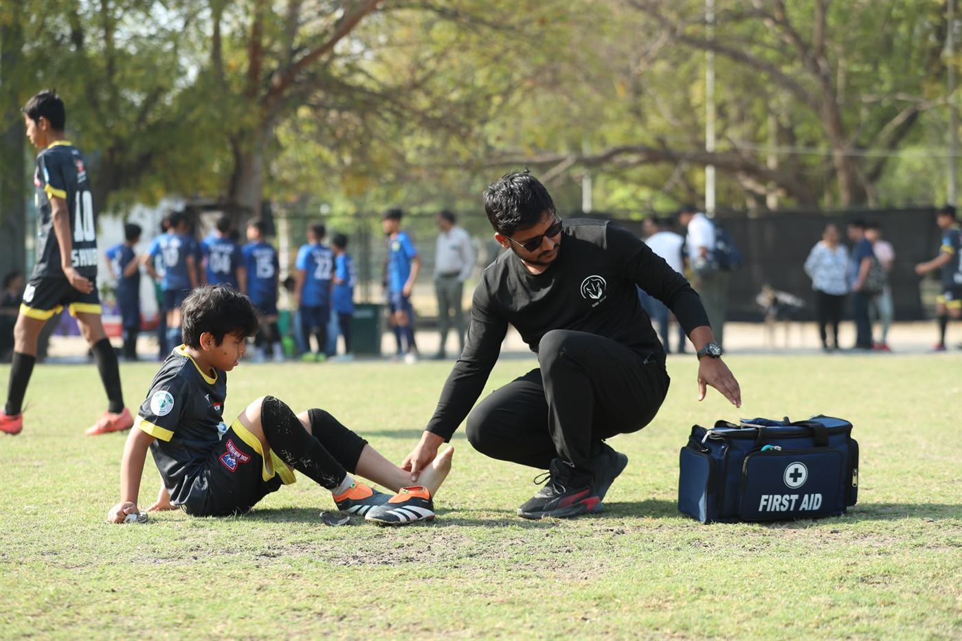 Dr. Sandeep assessing a young player's ankle during a junior match