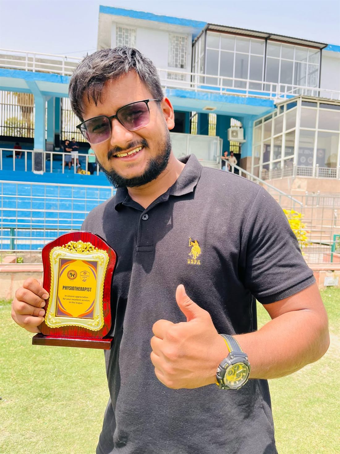 Dr. Sandeep holding a physiotherapist appreciation award at a stadium